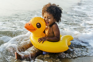 small girl inside inflatable duck in surf