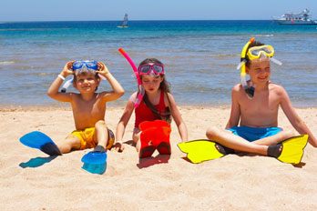 three children sitting on the sand at the beach